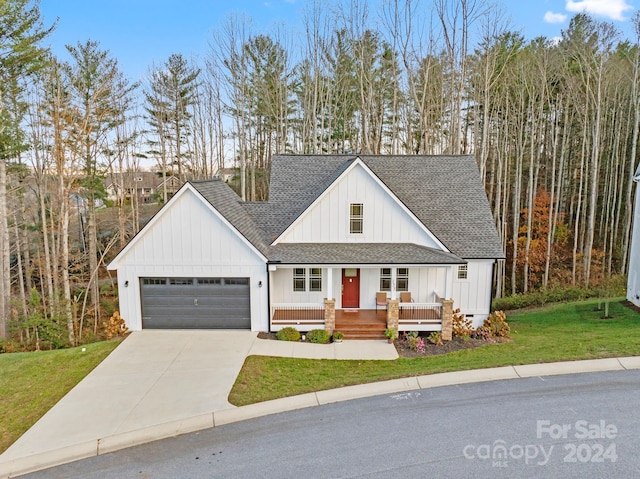 modern farmhouse featuring covered porch, a garage, and a front lawn