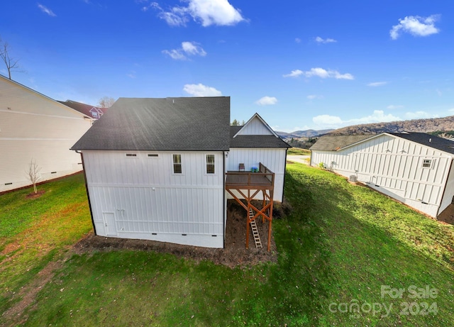 rear view of house with a deck with mountain view and a yard