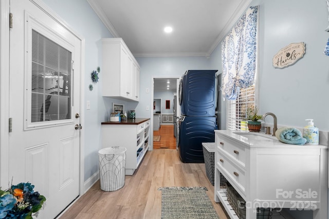 kitchen with white cabinets, light wood-type flooring, ornamental molding, and sink