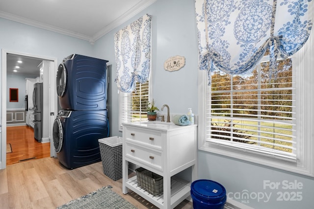 laundry room with crown molding, sink, light hardwood / wood-style floors, and stacked washer and clothes dryer