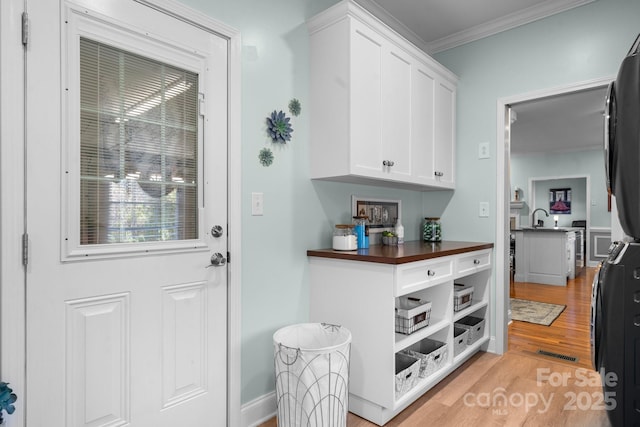 interior space featuring sink, light hardwood / wood-style flooring, stainless steel fridge, white cabinets, and ornamental molding