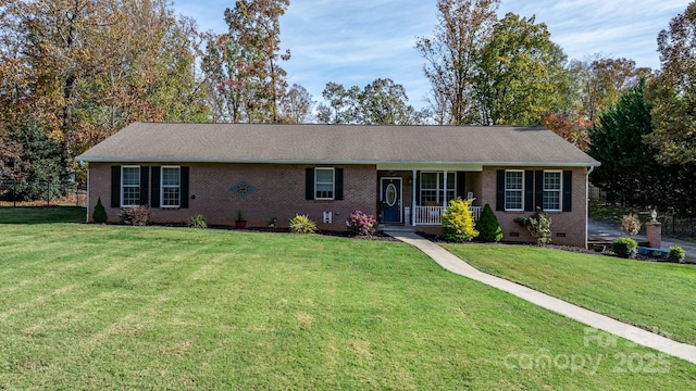 ranch-style house featuring covered porch and a front yard