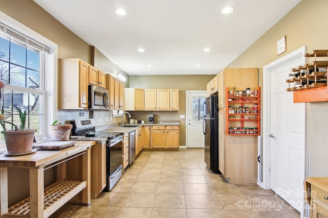 kitchen featuring wood counters, light brown cabinetry, sink, light tile patterned floors, and stainless steel appliances