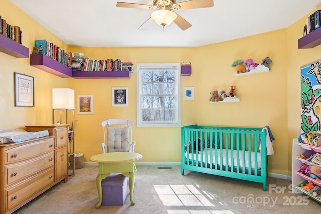 bedroom with a nursery area, light colored carpet, and ceiling fan