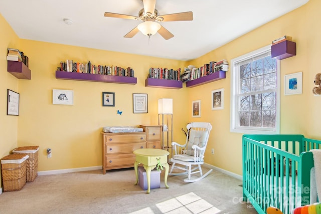 bedroom with a nursery area, ceiling fan, and light carpet