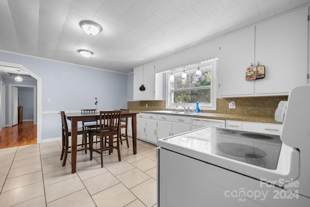 kitchen featuring light tile patterned floors, crown molding, backsplash, white cabinetry, and white appliances