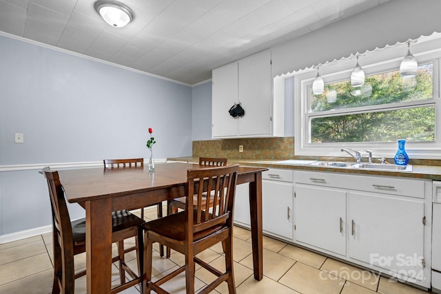 kitchen featuring ornamental molding, light tile patterned flooring, pendant lighting, sink, and white cabinets