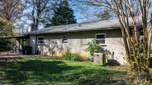 view of side of property with central air condition unit and a lawn