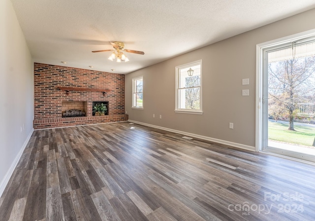 unfurnished living room featuring ceiling fan, a fireplace, dark wood-type flooring, and a textured ceiling