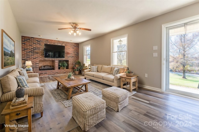 living room with a fireplace, wood-type flooring, and ceiling fan