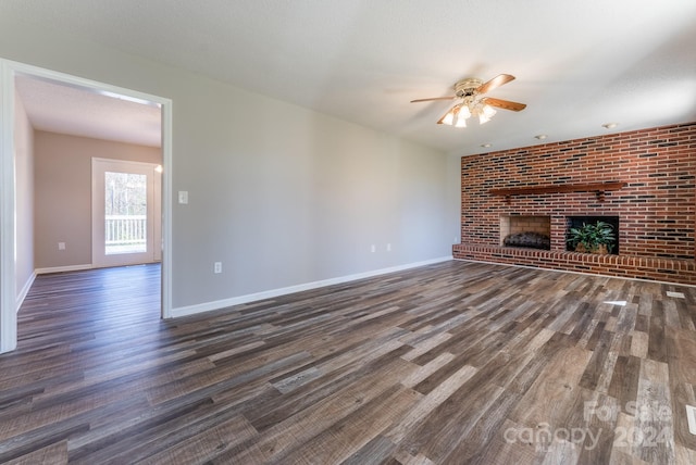 unfurnished living room featuring dark hardwood / wood-style floors, ceiling fan, a textured ceiling, and a brick fireplace