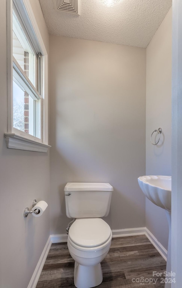 bathroom featuring hardwood / wood-style flooring, toilet, and a textured ceiling