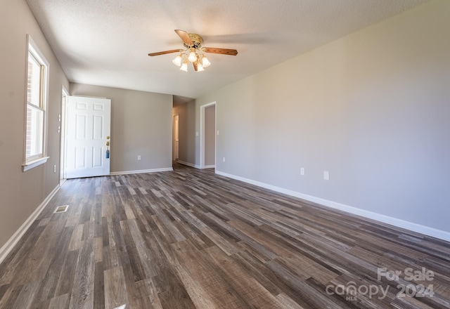 empty room with a textured ceiling, ceiling fan, and dark wood-type flooring