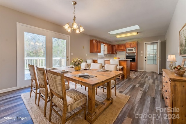 dining room with a skylight, dark hardwood / wood-style flooring, and a chandelier