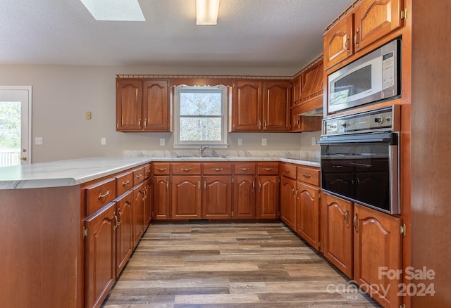 kitchen featuring kitchen peninsula, black oven, stainless steel microwave, and plenty of natural light