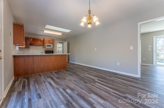 kitchen featuring kitchen peninsula, white microwave, dark wood-type flooring, an inviting chandelier, and oven