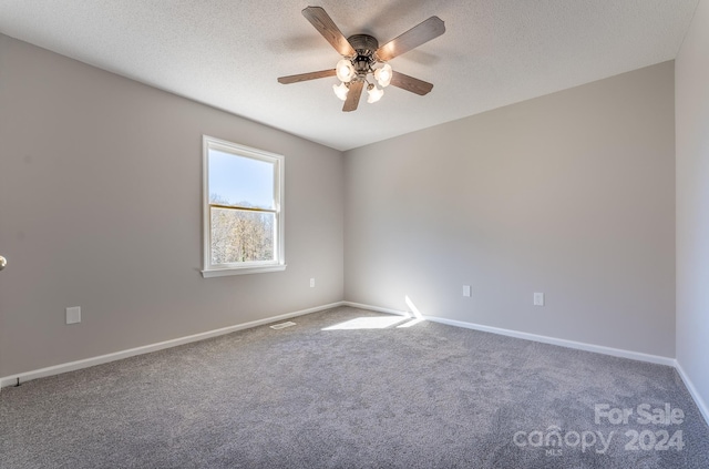 empty room with ceiling fan, carpet floors, and a textured ceiling