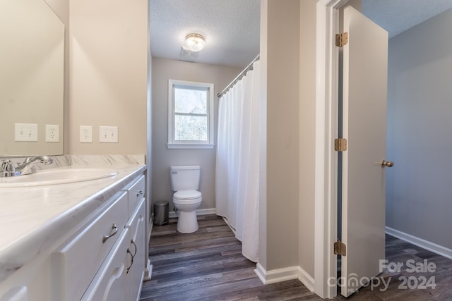 bathroom featuring vanity, a textured ceiling, hardwood / wood-style flooring, and toilet