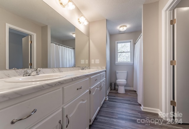 bathroom with hardwood / wood-style floors, vanity, toilet, and a textured ceiling