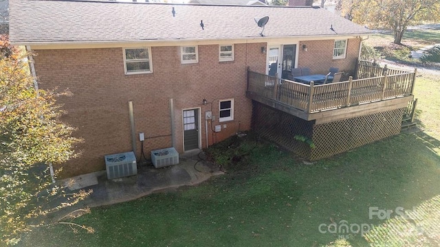 rear view of house with central AC unit, a deck, and a lawn