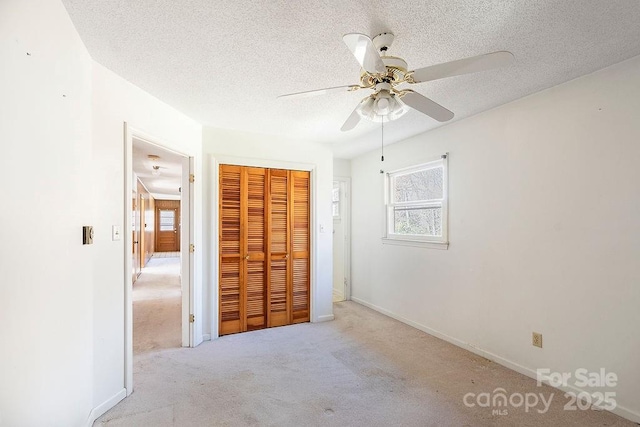 unfurnished bedroom featuring multiple windows, light colored carpet, a closet, and a textured ceiling