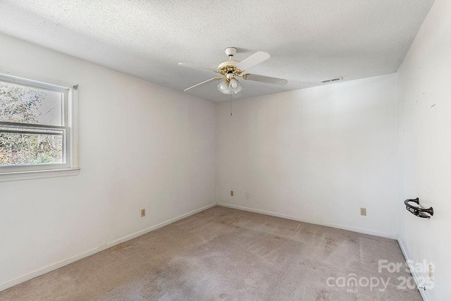 spare room with ceiling fan, light colored carpet, and a textured ceiling