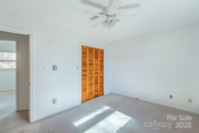 unfurnished bedroom with ceiling fan, light colored carpet, and a closet