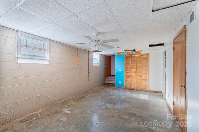 basement featuring plenty of natural light, a drop ceiling, and ceiling fan