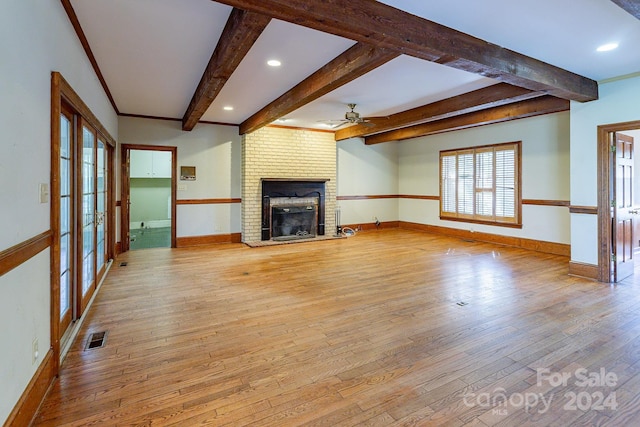 unfurnished living room featuring ceiling fan, light hardwood / wood-style flooring, beamed ceiling, and a brick fireplace