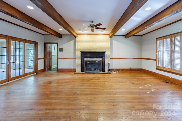 unfurnished living room with a fireplace, beam ceiling, and light hardwood / wood-style flooring