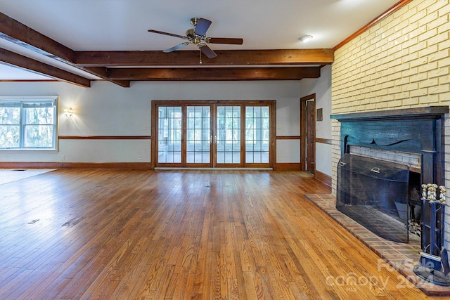 unfurnished living room with a fireplace, wood-type flooring, ceiling fan, and beamed ceiling