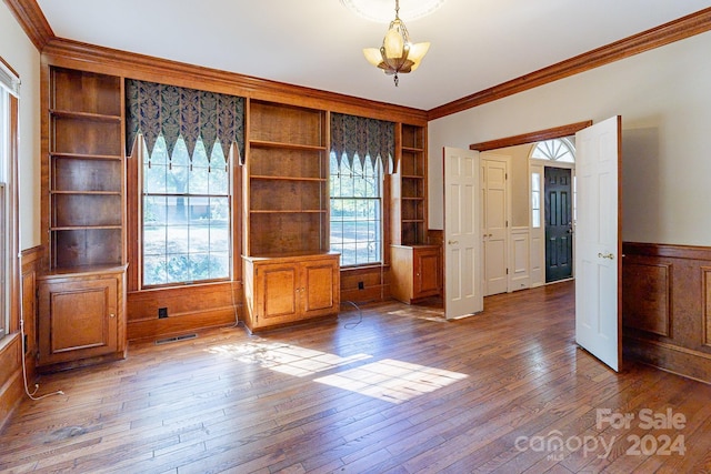 unfurnished dining area featuring hardwood / wood-style flooring, built in features, and ornamental molding