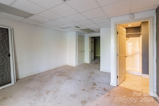 unfurnished bedroom with a drop ceiling and light carpet