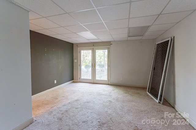 carpeted spare room featuring french doors and a drop ceiling