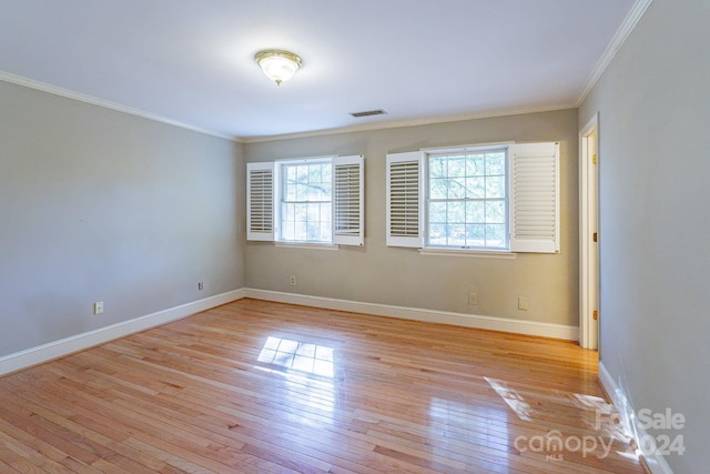 empty room featuring crown molding and light hardwood / wood-style flooring