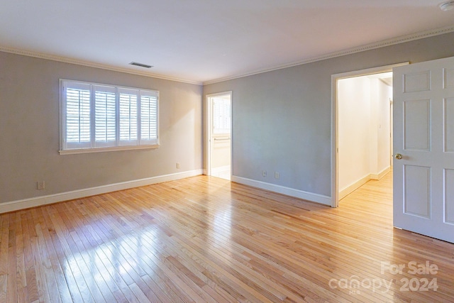 spare room featuring light wood-type flooring and ornamental molding