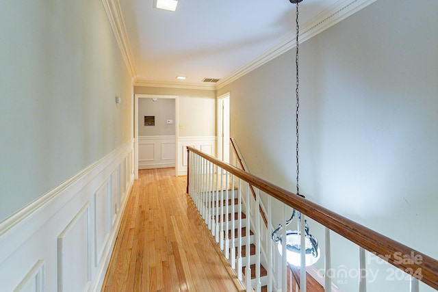 hallway with light wood-type flooring and ornamental molding