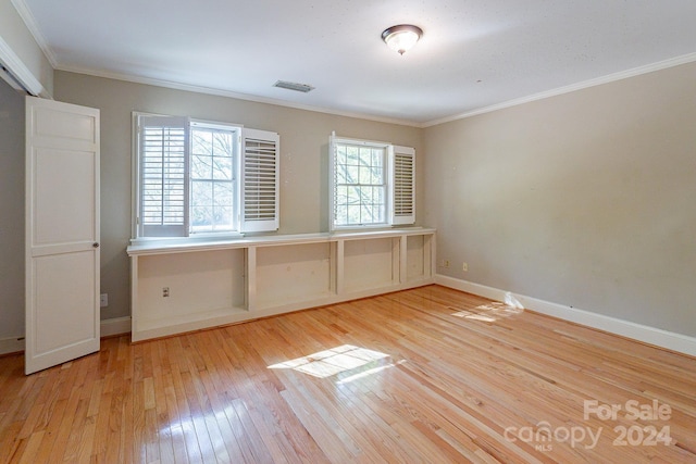 spare room featuring crown molding and light wood-type flooring