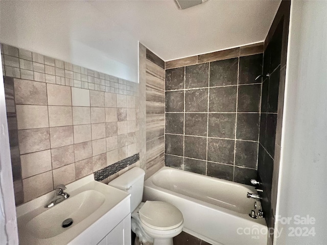 full bathroom featuring tiled shower / bath, vanity, tile walls, and toilet