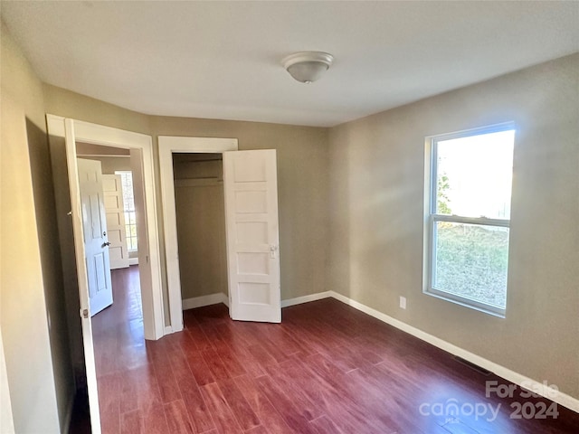 unfurnished bedroom with a closet and dark wood-type flooring