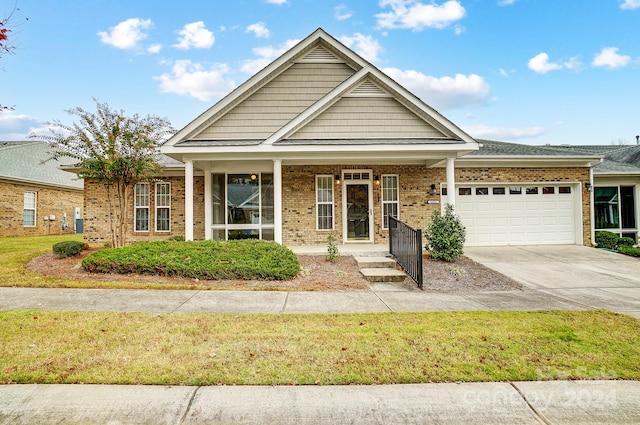 view of front of property with a front yard, a garage, and covered porch