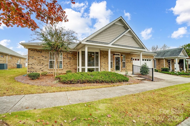 view of front of home featuring a porch, a garage, a front lawn, and cooling unit