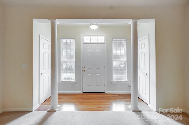 foyer featuring light wood-type flooring and decorative columns