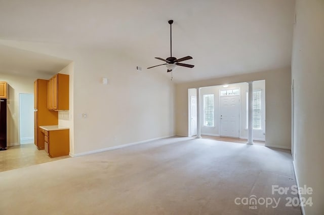 unfurnished living room with ceiling fan, light colored carpet, and a high ceiling