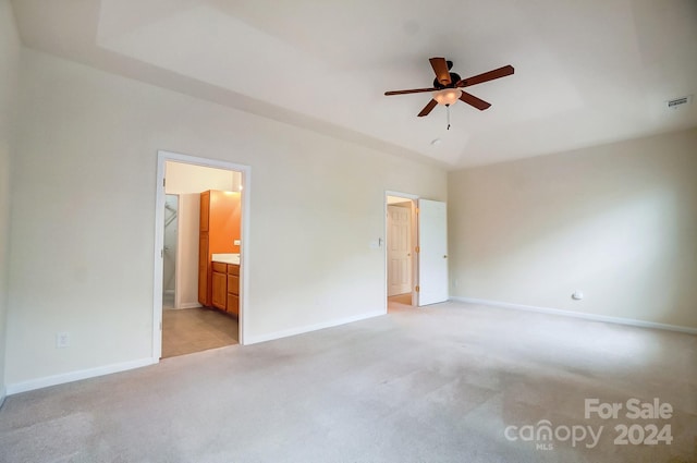 unfurnished bedroom featuring ceiling fan, light colored carpet, and ensuite bath