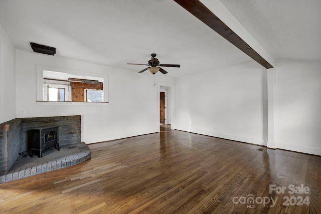 unfurnished living room featuring a textured ceiling, ceiling fan, beam ceiling, dark hardwood / wood-style floors, and a wood stove