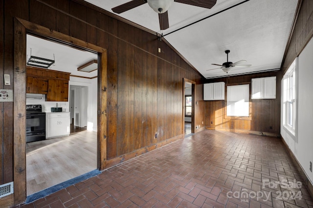 interior space featuring ceiling fan, lofted ceiling, and wood walls