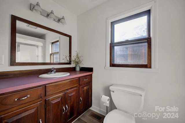 bathroom with hardwood / wood-style floors, vanity, toilet, and a wealth of natural light