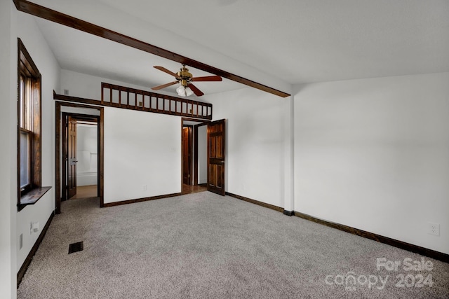 spare room with beamed ceiling, light colored carpet, and ceiling fan