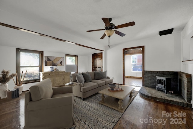 living room with dark hardwood / wood-style floors, a healthy amount of sunlight, a wood stove, and ceiling fan